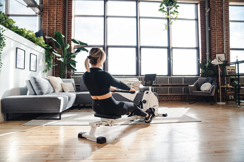 woman working out on a rowing machine in apartment